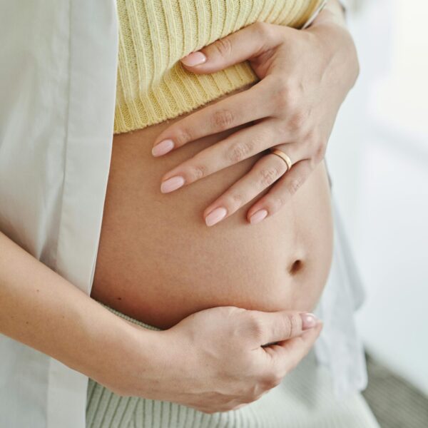 A close-up shot of a pregnant woman's hands gently resting on her belly, symbolizing motherhood.